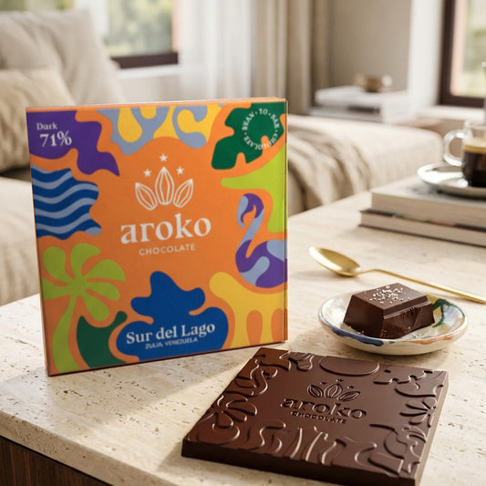 Confezione e tavoletta di cioccolato fondente Sur del Lago 71% Aroko 50 g in scena ambientata, con quadretti su un piattino