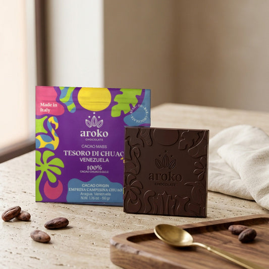 Confezione e tavoletta di cioccolato fondente Tesoro di Chuao D.O.C.C. Aroko 50 g in scena ambientata, con fave di cacao