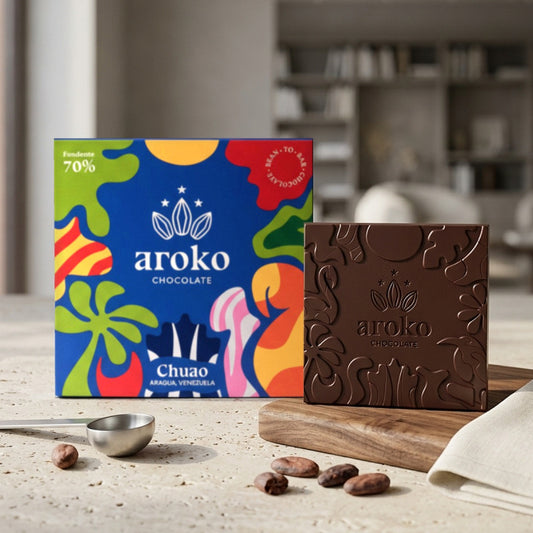 Confezione e tavoletta di cioccolato fondente Chuao 70% Aroko 50 g in scena ambientata, con fave di cacao